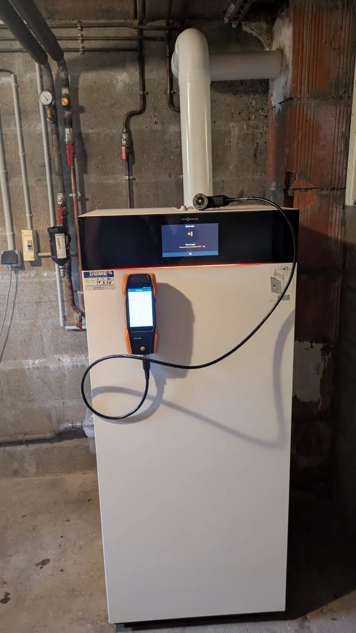 Analyseur de combustion branché sur une chaudière murale pendant la mise en service
